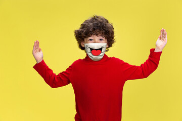 Huge shows. Portrait of little boy with emotion on his protective face mask on studio background....