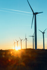 Wind Turbines at Dusk. Landscape sunset with windmills. Renewal source of electricity. Wind turbines field new technology for clean energy on mountain, sunset view with colorful twilight on sky.