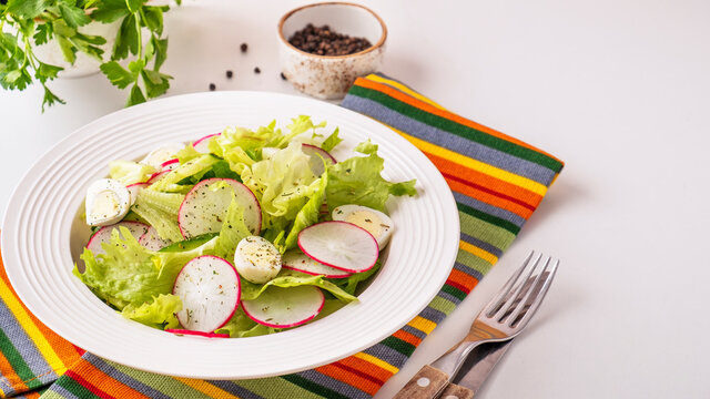Vegetables salad with cucumbers, quaill eggs and radish on a white plate. Copy space