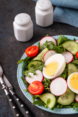 Healthy salad with eggs and fresh vegetables on a plate. Closeup