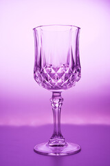 Wineglass on the light background. Fine cristal glassware concept. Vertical, toned in pink