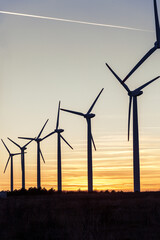 Fototapeta premium Wind Turbines at Dusk. Landscape sunset with windmills. Renewal source of electricity. Wind turbines field new technology for clean energy on mountain, sunset view with colorful twilight on sky.