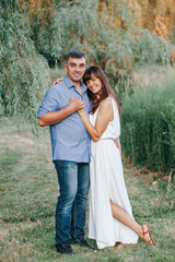 Fototapeta premium Beautiful smiling couple man woman in love. Husband and wife hugging in park on summer day at sunset. Togetherness and happiness. Authentic real people family outdoors.