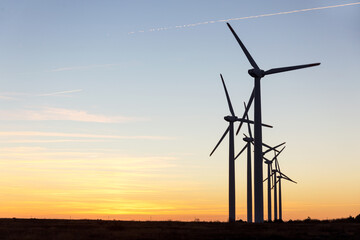 Wind Turbines at Dusk. Landscape sunset with windmills. Renewal source of electricity. Wind turbines field new technology for clean energy on mountain, sunset view with colorful twilight on sky.