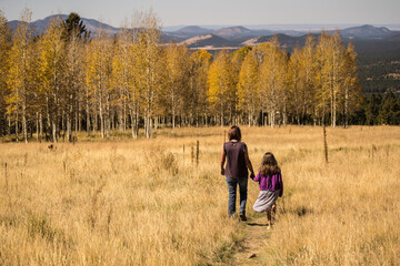 Mother and Daughter walking in field with aspen trees in the fall in Flagstaff, Arizona, USA