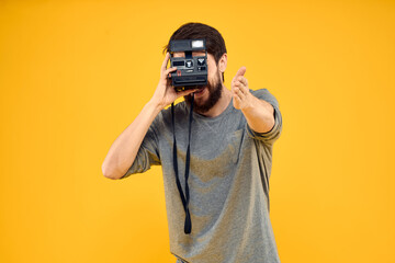 Male photographer with professional photo camera. Professional Creative approach studio yellow background