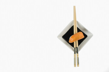 Close-up of nigiri sushi with chopsticks and a bowl of soy sauce
