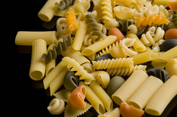 Close-up of various raw pasta on a black background