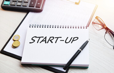 The inscription START-UP. Handwritten text in a notebook on the background of financial tables.
