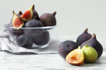 Tasty fresh purple and green figs on white marble table, space for text