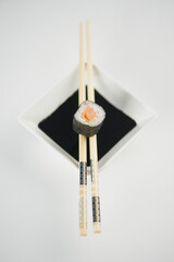 Close-up of a futomaki sushi with chopsticks and a bowl of soy sauce