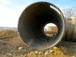 Old rye pipes of large diameter lie on the ground. Pipeline. Large iron drainage pipes connect two...