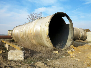 Old rye pipes of large diameter lie on the ground. Pipeline. Large iron drainage pipes connect two...