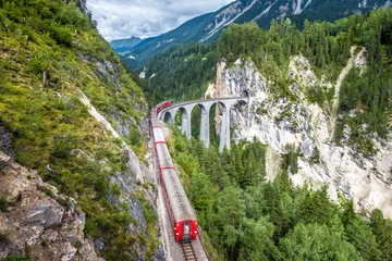 Photo sur Plexiglas Viaduc de Landwasser Le train express Bernina circule sur le viaduc de Landwasser dans les Alpes, en Suisse. Chemin de fer dans les montagnes suisses.