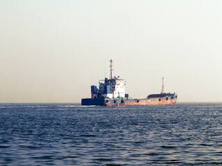 Obraz premium Old cargo ship goes to the industrial and commercial port for cargo loading and further transportation. Shipping, Transportation, Logistic Import Export background