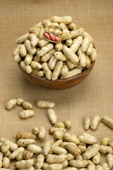 Peanuts in a bowl in jute background.
