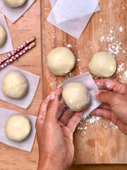 Dough balls being prepared on a wooden table top