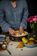 Step by step process of making frangipani tart with pear, hazelnuts and chocolate. Adding sliced pears.