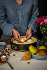 Step by step process of making frangipani tart with pear, hazelnuts and chocolate. Adding sliced pears.