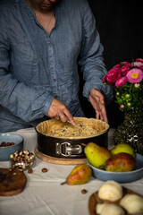 Step by step process of making frangipani tart with pear, hazelnuts and chocolate. Adding frangipani filling.