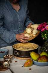 Step by step process of making frangipani tart with pear, hazelnuts and chocolate. Adding sliced pears.