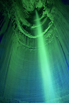 Tall waterfall in a dark cavern with green lighting