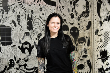 Young woman with black hair standing in front of a black and white background