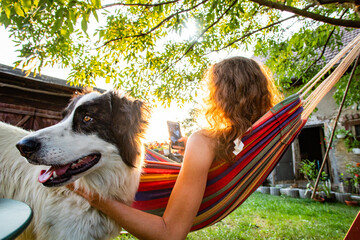 woman with dog relaxing in hammock in back yard - Powered by Adobe