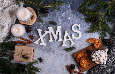 Christmas card. Wooden inscription xmas burning candles, fir branches, cocoa. Flat lay.