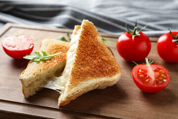Tasty toast sandwiches with cheese and tomatoes on wooden board