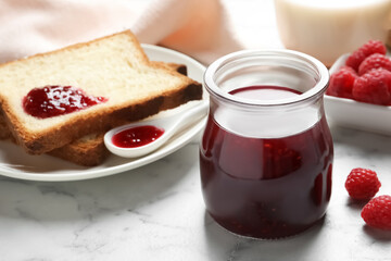 Sweet raspberry jam and toasts for breakfast on white marble table