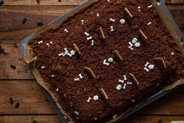 Kuchen als Friedhof mit Gräbern und Skeletten aus Schokokrümel, Creme und Banane auf Tisch aus...