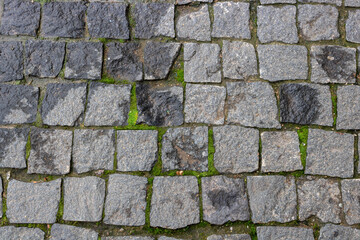 Granite paving stone background of the sidewalk. Abstract background of an old cobblestone street close-up