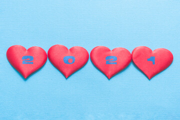 Four red hearts on a blue background. The numbers 2021 are written on the hearts.