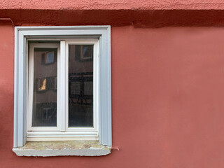 Fenster, weißer Stuck- Rahmen in roter Hausfassade