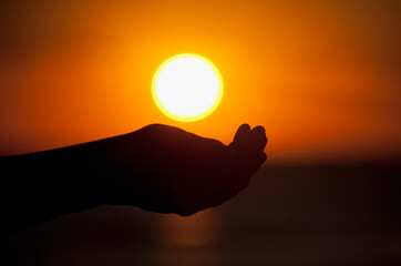 Person's hands cupping under setting sun, Miami Beach, Florida, USA