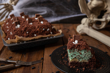 Kuchen als Friedhof mit Gräbern und Skeletten aus Schokokrümel, Creme und Banane auf Tisch aus...
