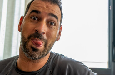 Fototapeta premium Portrait of middle-aged man with beard sticking out his tongue