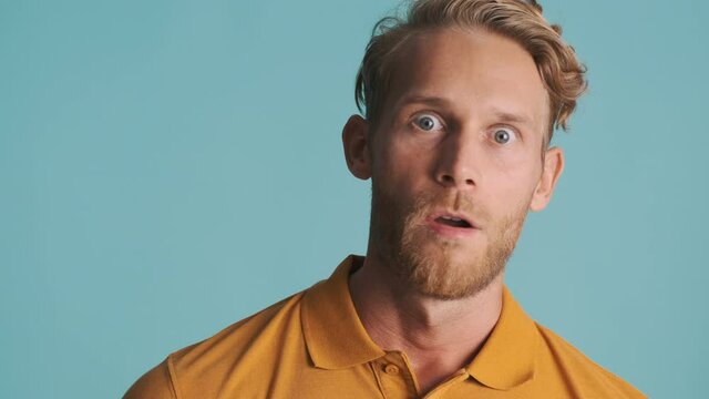 Shocked blond bearded man amazedly looking in camera over colorful background. Wow expression
