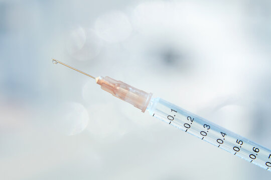 Close up macro photograph of medical syringe with vaccine droplet 