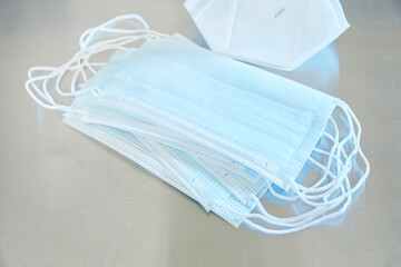 Stack of blue surgical medical masks and KN95 mask on stainless steel surface 