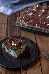 Kuchen als Friedhof mit Gräbern und Skeletten aus Schokokrümel, Creme und Banane auf Tisch aus Holz und dahinter Spinnweben