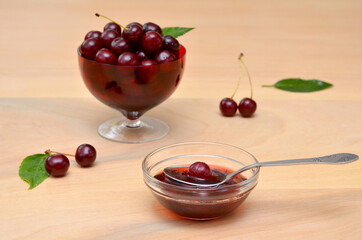 beautiful still life of jam in glass and cherries in a bowl on the table 