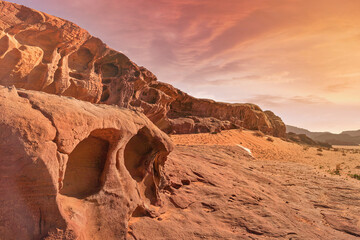 Red sandstone rocks formations lit by orange afternoon sun in Wadi Rum (also known as Valley of the...