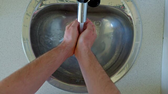 Man washing hands in metal sink