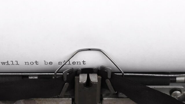 typing a quote we will not be silent on a vintage typewriter close-up