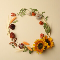 Dried flowers and leaves arranged in shape of wreath on beige background, flat lay with space for text. Autumnal aesthetic