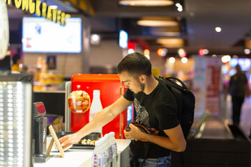 The guy takes out cash to pay at the cash desk of fast food.