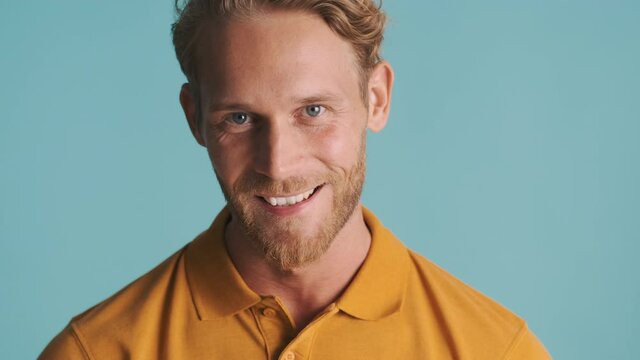 Young attractive blond bearded man happily posing on camera over colorful background