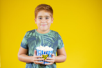 Young child eating popcorn on yellow background